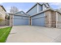 Attached two car garage with blue doors, brick accents, and a spacious driveway for easy parking at 907 Eldorado Dr, Superior, CO 80027
