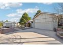 Home exterior featuring an attached two-car garage, carport, brick accents, and mature landscaping in a sunny, blue-sky setting at 2287 Pinto Trl, Elizabeth, CO 80107