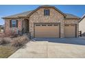 Charming home exterior featuring stone facade and a three car attached garage and a concrete driveway at 23709 E Caleb Pl, Aurora, CO 80016