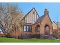 Charming brick home featuring an arched entry, Tudor accents, and a well-manicured lawn at 2960 Ash St, Denver, CO 80207