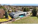 An aerial view of a home with a large yard, a patio with furniture, and a swimming pool at 49 Charlou Cir, Cherry Hills Village, CO 80111