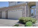 Brick home featuring an attached two-car garage, covered entryway, and manicured front yard at 973 Orion Way, Castle Rock, CO 80108