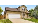 Traditional home featuring attached two car garage, landscaped lawn, and covered entryway at 19259 E Caspian Pl, Aurora, CO 80013