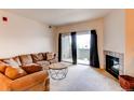 Bright living room featuring a cozy couch, fireplace, and balcony access at 908 S Yampa St # 208, Aurora, CO 80017