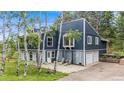 Two-story home with black siding, light gray trim, stone patio and two-car garage at 8783 S Ault Ln, Morrison, CO 80465