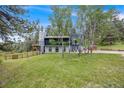 View of back of house with black siding, light gray trim, stone patio and sloped yard at 8783 S Ault Ln, Morrison, CO 80465