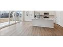 Open-concept space with kitchen, stainless appliances, island, and floor-to-ceiling sliding glass doors to patio at 841 Alpine Ridge St, Erie, CO 80516