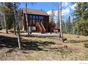 Charming cabin with a deck and stairs amongst birch trees, perfect for mountain living and entertaining at 10438 Sunlight Ln, Conifer, CO 80433