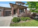 Charming front porch shows brick columns, a cozy seating area, and manicured landscaping at 16062 Red Bud Loop, Parker, CO 80134