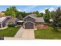 Aerial view showcasing a well-kept lawn, two-car garage, and a peaceful setting surrounded by mature trees at 10859 W Fair Ave, Littleton, CO 80127