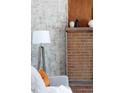 Close up of brick fireplace with white mantel featuring modern decor, next to a floor lamp at 8100 W 8Th Ave, Lakewood, CO 80214