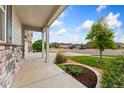 Covered front porch with stone accents providing a welcoming entrance to the home at 15525 Quince Cir, Thornton, CO 80602
