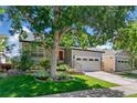 Charming exterior with a well-maintained lawn, mature tree and attached two car garage at 6055 W Progress Ave, Littleton, CO 80123