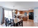 Eat-in kitchen featuring warm wood cabinets, stainless steel appliances, and space for dining at 11537 Macon St, Commerce City, CO 80640