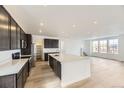 Spacious kitchen with an island, stainless steel appliances, dark cabinets, and bright natural light at 8867 Waterleaf Ln, Littleton, CO 80125