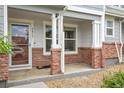 Cozy covered front porch featuring brick pillars, neutral siding, and direct access into the home at 5813 Ceylon St, Denver, CO 80249