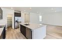 Bright kitchen with island, stainless steel appliances, quartz countertops, and hardwood floors at 6751 Arbor E Blvd, Thornton, CO 80602