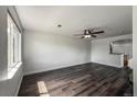 Spacious living room featuring wood-look flooring, large windows, and modern ceiling fan at 12783 Ivy St, Thornton, CO 80602