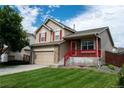 Inviting two-story home featuring a two-car garage, manicured lawn, and a covered front porch at 10534 Ursula St, Commerce City, CO 80022
