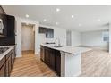 Bright kitchen boasts modern appliances, dark cabinetry, quartz countertops, a large island, and an open floor plan at 1290 Loraine N Cir, Lafayette, CO 80026