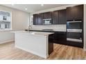 Modern kitchen features stainless steel appliances, dark cabinetry, a large island, and wood flooring at 1290 Loraine N Cir, Lafayette, CO 80026