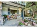Inviting front porch with chairs and a table, surrounded by colorful flowers and decorative stone at 4338 S Alton St, Greenwood Village, CO 80111