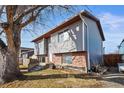 Side view of home with gray siding, brick foundation, and front yard at 221 Jackson Ave, Firestone, CO 80520