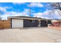 Single story home with a spacious driveway, attached garage, and a striking dark gray exterior under a bright sky at 9101 Clarkson St, Thornton, CO 80229