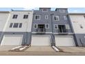 Rear view of modern townhomes featuring white garage doors and blue siding at 14265 Currant St, Broomfield, CO 80020