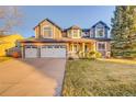 Charming two-story home with a three car garage, manicured lawn, and inviting covered front porch at 7128 Orchard St, Arvada, CO 80007