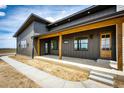 Beautiful home exterior showcases a covered porch with wood beams and a pathway leading to the inviting entrance at 65960 E Evans Pl, Byers, CO 80103