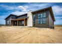 A modern exterior design with a stone chimney, large windows, and a covered porch perfect for relaxation at 65960 E Evans Pl, Byers, CO 80103