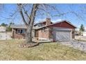 Inviting home featuring a brick facade, two-car garage, and a large tree in the front yard at 4080 E Caley Cir, Centennial, CO 80121