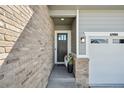 Inviting front entry with a modern front door, brick accents, and an attached two-car garage at 6980 S Yantley Ct, Aurora, CO 80016