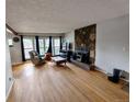 Cozy living room with hardwood floors, large windows, stone fireplace, and neutral paint at 7409 Pierce St, Arvada, CO 80003