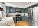 Modern kitchen featuring updated appliances, granite countertops, and stylish sage cabinets with light-colored walls and natural lighting at 6662 Fonder Dr, Parker, CO 80134