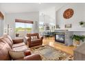 Open-concept living room featuring a fireplace, hardwood floors, high ceilings, and seamless access to the dining area with lots of natural light at 6662 Fonder Dr, Parker, CO 80134