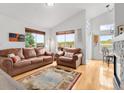 Bright living room with high ceilings, hardwood floors, large windows, and comfortable leather furniture creating an inviting atmosphere at 6662 Fonder Dr, Parker, CO 80134