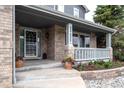 Inviting front porch with brick accents, decorative plants, and seating area at 14962 Williams St, Thornton, CO 80602