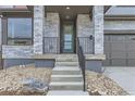 Inviting front entrance featuring a green door, stone pillars, black iron railing, and freshly landscaped yard at 5575 Moosehead Cir, Longmont, CO 80503