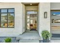 Inviting entrance with modern glass door, stone accents, and interior chandelier view at 936 Sunflower St, Louisville, CO 80027