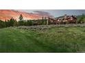 Expansive home exterior with large lawn and landscaping at sunset, providing a peaceful mountain setting at 220 Cottonwood Cir, Breckenridge, CO 80424