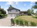 Attractive home with a sloped lawn, mature trees, a two-car garage, and a gray exterior at 9383 W Colorado Ave, Lakewood, CO 80232