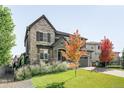 Inviting two-story home with stone details, well-kept lawn, and colorful autumn foliage at 6938 E Lake Dr, Centennial, CO 80111