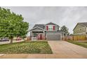 Inviting two-story home with gray siding, red door and shutters, a well-kept lawn, and an attached two-car garage at 1488 N Stratton Ave, Castle Rock, CO 80104