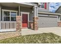 Inviting front entrance with a red door, brick accents, and a cozy porch, enhancing curb appeal and charm at 1488 N Stratton Ave, Castle Rock, CO 80104
