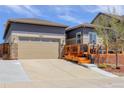 Exterior view of home with two-car garage and outdoor deck featuring wood and stone design elements at 18027 Telford Ave, Parker, CO 80134