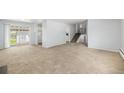 Open living room with plush carpet, sliding glass doors, and stairs leading to the second floor at 387 Tucson St, Aurora, CO 80011
