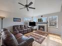 Inviting living room with a cozy fireplace, large windows, hardwood floors, and comfortable leather seating at 6348 Deframe Way, Arvada, CO 80004