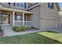 Welcoming covered front porch showcasing classic white railing, brick accents, and manicured landscaping at 23500 Bent Oaks Way, Parker, CO 80138